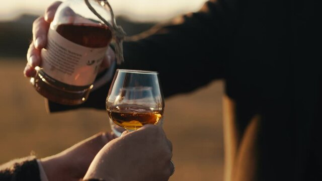 Couple pouring rum during golden hour in nature