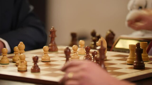 Closeup of a chessboard while  businessmen playing speed chess on it.