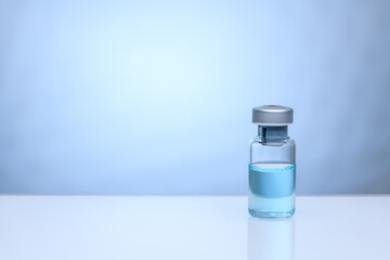 The Coronavirus Vaccine. A bottle of vaccine against coronavirus on a blue background. The concept of protection against coronavirus infection, COVID-19