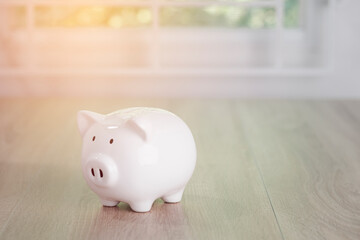 A white piggy bank sits on a wooden table