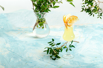 A glass of cold italian limoncello garnished with citrus slices on the blue decorated background