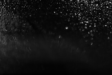 Water droplets on glass at night, dark background. Black and white texture. Defocus and blur. High quality photo