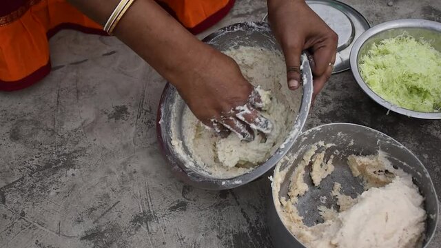 Indian woman is preparing mixture Daler bori in a bowl in sunny day. It is a form of dried lentil dumplings popular in Bengali cuisine.