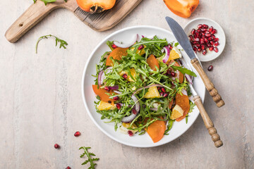 Delicious persimmon salad with arugula  and orange served on light grey table, flat lay. Space for...