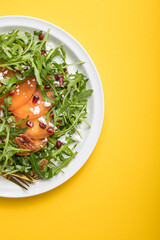 Persimmon salad with arugula, nuts, goat cheese, pomegranate. Healthy vegetarian food salad concept.