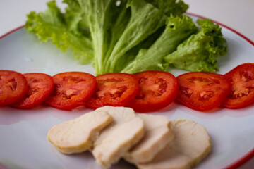 Tasty diet breakfast on a plate salad leaves, sliced tomatoes and boiled chicken brisket