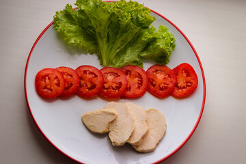 Tasty diet breakfast on a plate salad leaves, sliced tomatoes and boiled chicken brisket