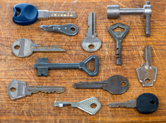 Many assorted old multi-colored metal antique vintage keys of different shapes on wooden scratched table background.