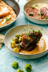 Lamb meat on the bone in sauce and brussels sprouts on the blue background