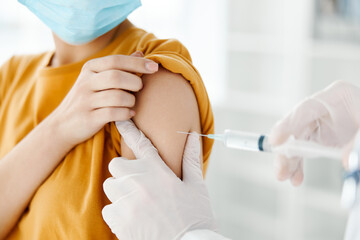 side view of doctor injecting vaccine into shoulder of patient wearing medical mask covid 