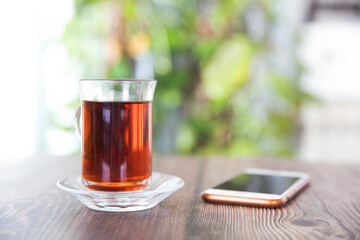 A cup of black tea and a mobile phone