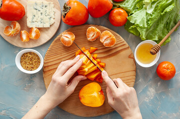 Ingredients and the process of making a vitamin winter salad with persimmons, tangerines and blue...