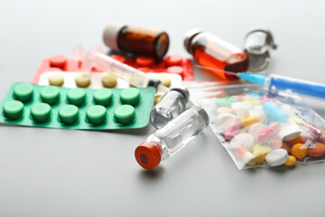 Ampoules and different pills on grey background