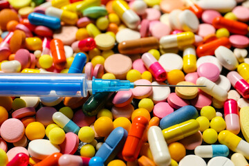 Syringe with different pills, closeup
