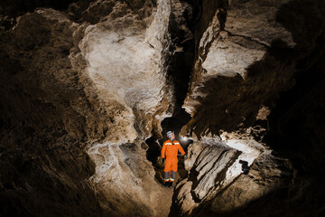 Obraz premium Speleologist descend by the rope in the deep vertical cave tunnel. Karst cave