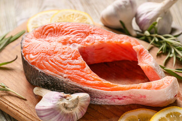 Raw salmon steak with garlic and lemon on wooden background