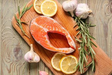 Raw salmon steak with garlic and lemon on wooden background
