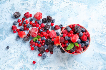 Bowl with different frozen berries and fresh mint on color background