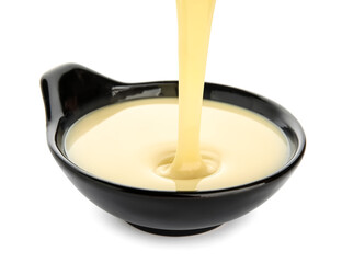 Sweet condensed milk pouring into bowl on white background
