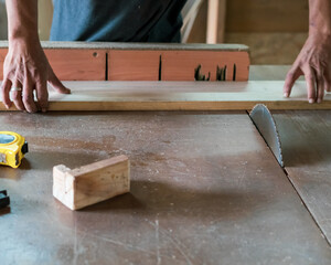 A man cuts wood on a circular saw in a carpenter workshop.