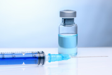 The coronavirus vaccine and syringe injection. Vial with vaccine against coronavirus on a light blue background. The concept of protection against coronavirus infection, COVID-19.