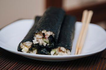 Home rolls. Rice and fish wrapped in nori seaweed on a white plate.