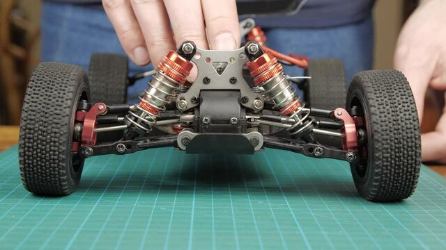 Close-up radio control model buggy car. The hands of the master checking the suspension of model