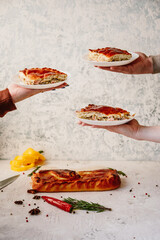 A pie of salmon (red fish) and rice lies on the table, and above the table, female hands hold a piece of pie on a plate