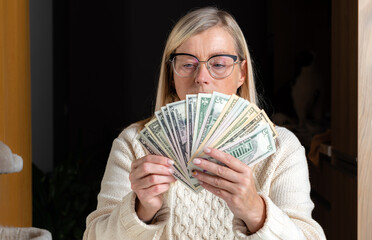 surprised female employee sitting at work and looking at dollar banknotes,  financial welfare concept