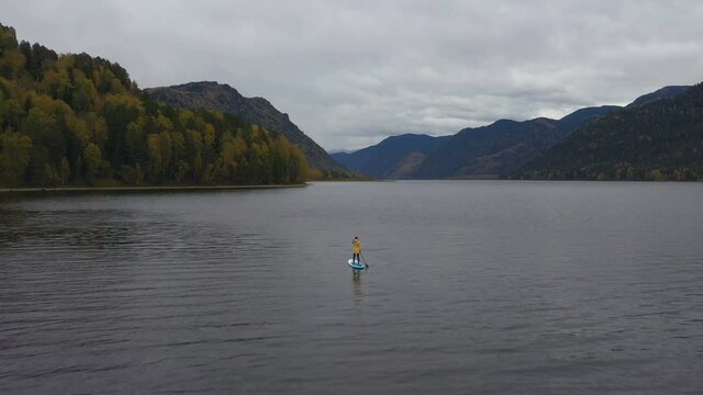 Woman Paddling on SUP Board on Teletskoye Lake in Altai Mountains, Siberia, Russia. Drone Shot.
