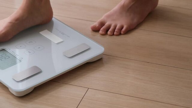 白い体重計に乗る女性