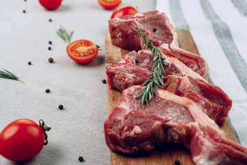 Raw t-bone steak on wooden cutting board on wooden table