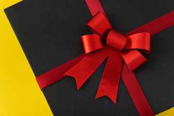 Black box with red bow close up. Elegant gift.