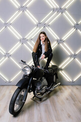 Plakat Young fashion girl posing in black leather with motorcycle.