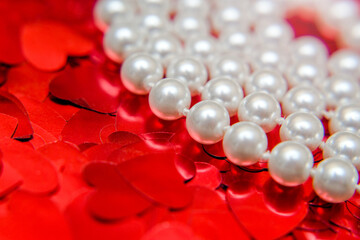 Pearl necklace on a background of red hearts