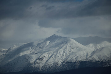 Fototapeta na wymiar mountain pick with snow on top clouds ice winter background in mitsikeli mountain grreece