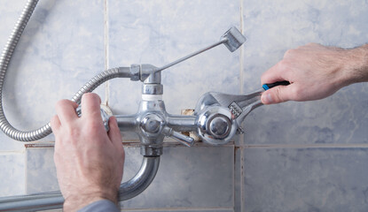 Man repair and fixing shower faucet in bathroom.