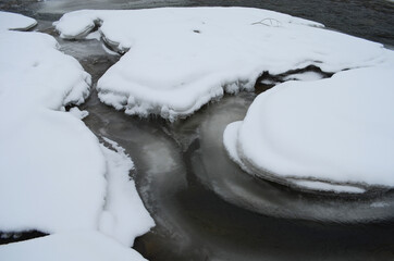 mountain river in wintertime. carpathian landscape with spruce forest and snow covered shore ukraine