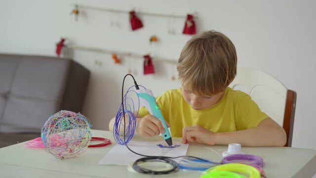 Close Up shot of a little boy that is using a 3d pen
