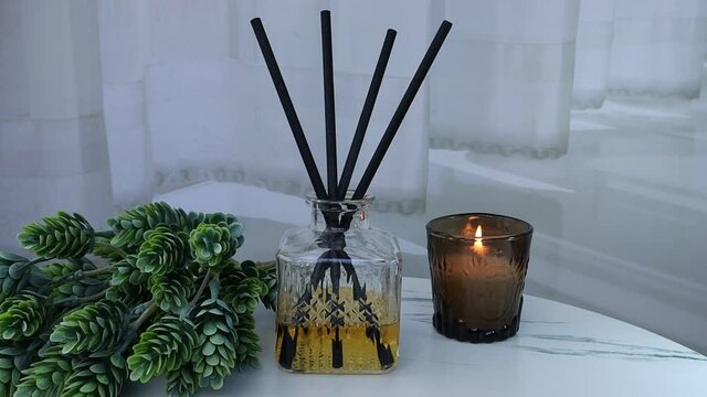 aroma scented reed diffuser glass is on the white marble table with scented candle glass with background of curtain to creat romantic and realx ambient in bedroom on valentine day