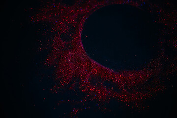 Red sun made of sequins. Scattered sequins on a black background. Space texture.