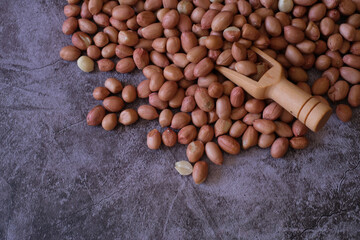 Raw Groundnuts on cement background with wooden scoop. Top view. copy space for text.