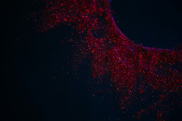Red sun made of sequins. Scattered sequins on a black background. Space texture.