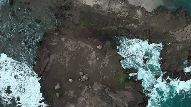 Top down aerial view of clear blue ocean with foamy wave. Taken from drone flying over the shoreline