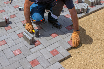 A builder installs concrete blocks for sidewalks in the courtyard of a country house. Selective focus.