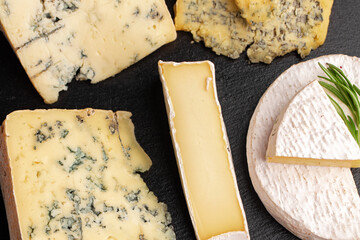 Several different pieces of cheese served on black stone flat plate