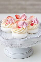 Fototapeta na wymiar Mini pavlova cakes with chocolate hearts, fresh strawberries and red heart shaped sprinkles