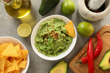 Concept of tasty eating with guacamole and ingredients on gray background
