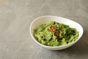 Bowl of guacamole on gray background, space for text
