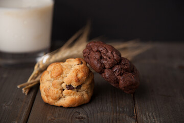 Cookies on a wooden table with a glass of milk and wheat ear